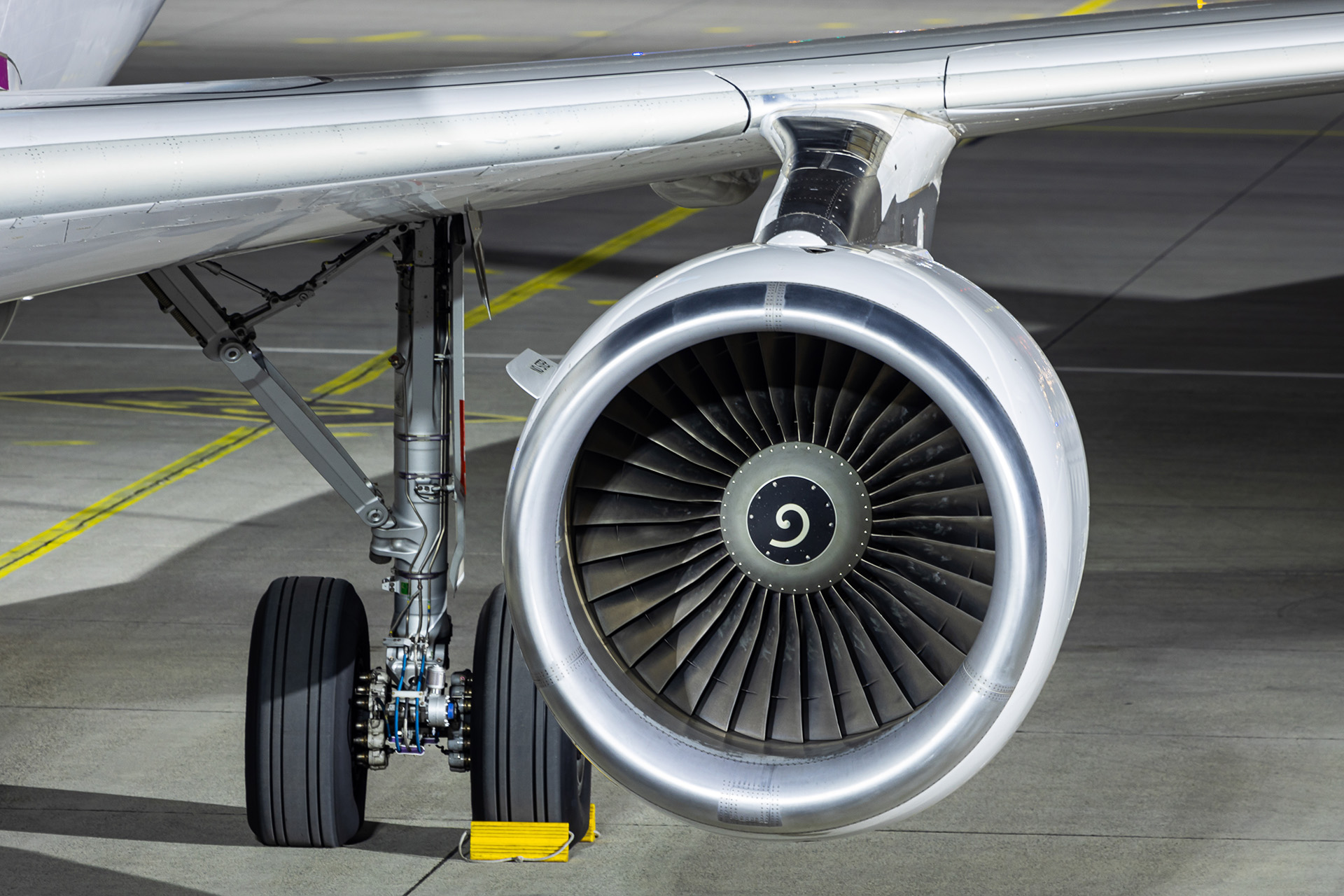 Closeup of jet engine and main gear of an Airbus A320. Airplane parked at night at the apron